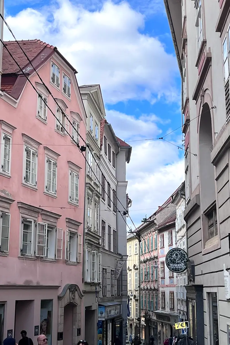 View of Sporgasse shopping street in Graz lined with historic buildings, cafés, and local shops.