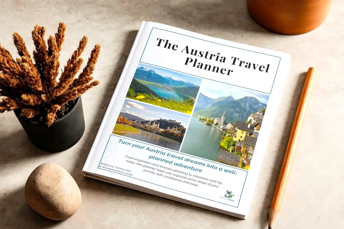 The Austria Travel Planner sitting on a desk with a pencil and a plant next to it
